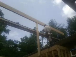 Carpenter setting a ridge beam over a new addition frame in Medon