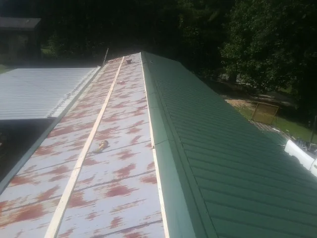 Old rusted panels beside newly installed green metal roofing — Wind Damage Roof Repair by Roofing Brothers in Medon