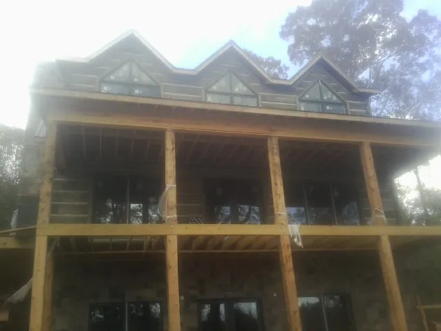 Dormers and porch framing on a large log home under construction — Roof Coating work by our crew in Medon