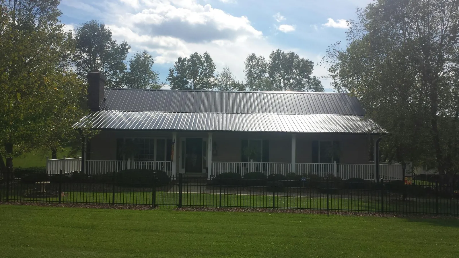 Gray metal roof on a brick ranch with a full width front porch — Gutter Guard Installation work by our crew in Medon