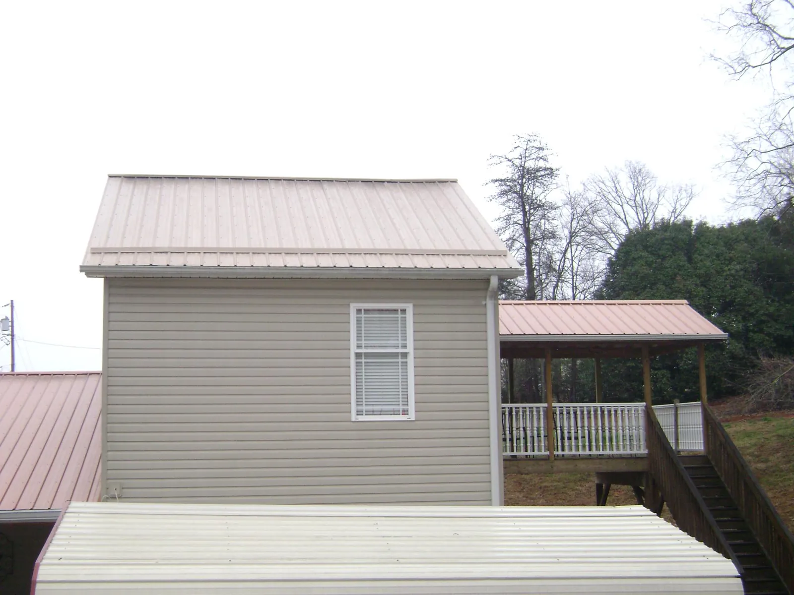 Tan metal roofs on a two story addition and attached porch, from a Roof Replacement job in Medon
