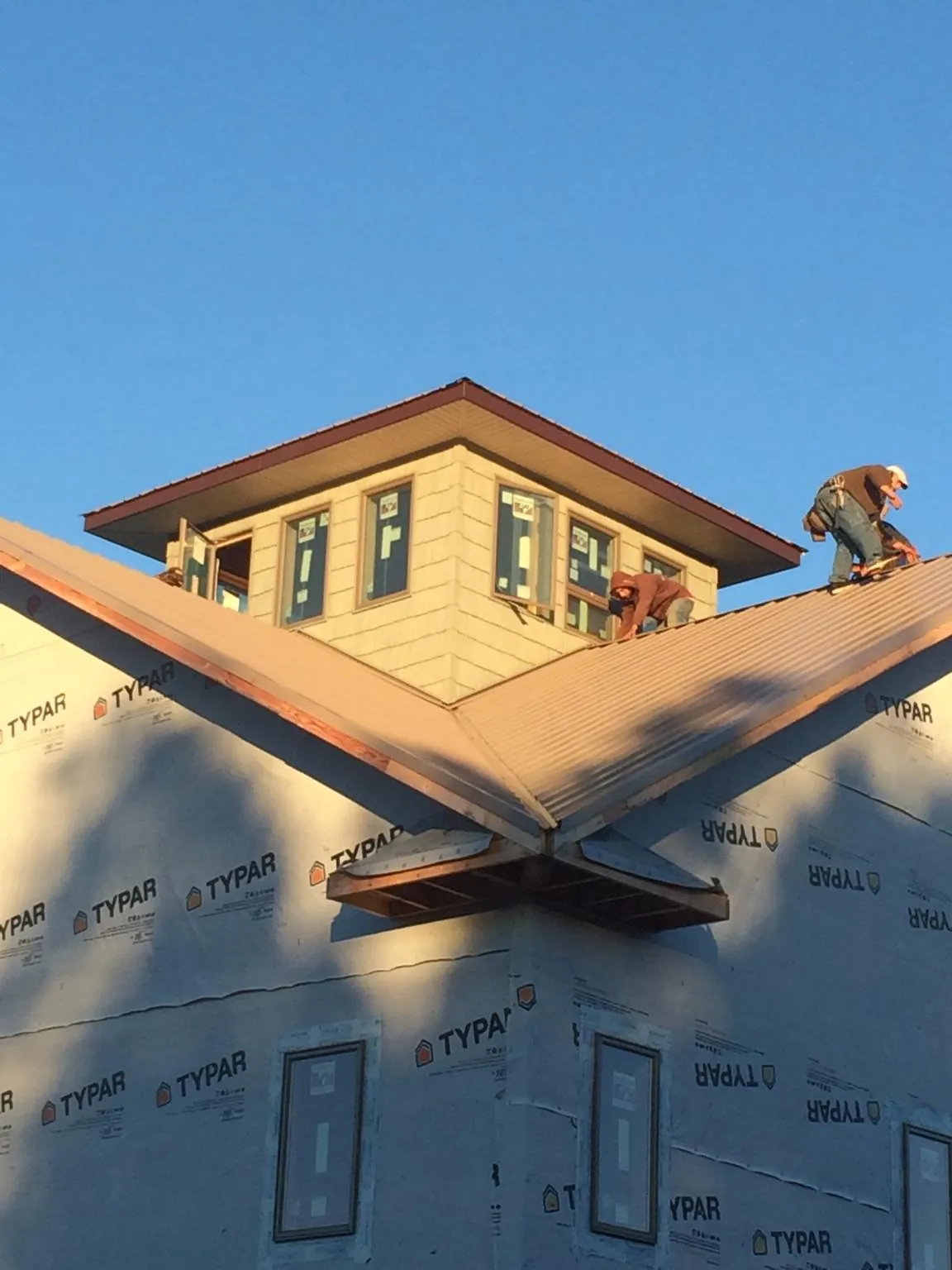 Roofers working around a rooftop cupola on a new metal roof at sunset — Roof Waterproofing in Medon by Roofing Brothers